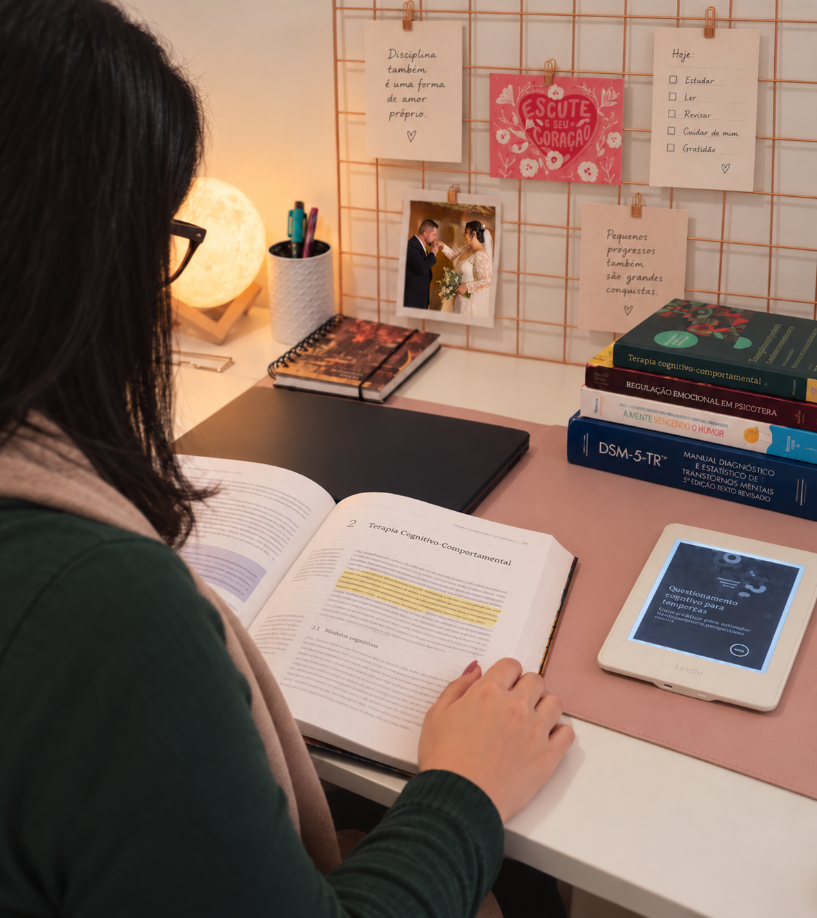 Carolina estudando terapia cognitivo-comportamental em uma escrivaninha com livros clínicos e materiais de estudo